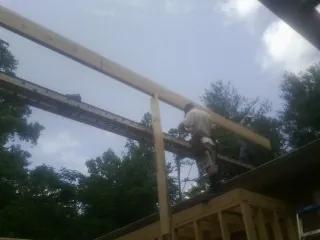 Carpenter setting a ridge beam over a new addition frame — Ice Dam Removal by Roofing Brothers in Campus