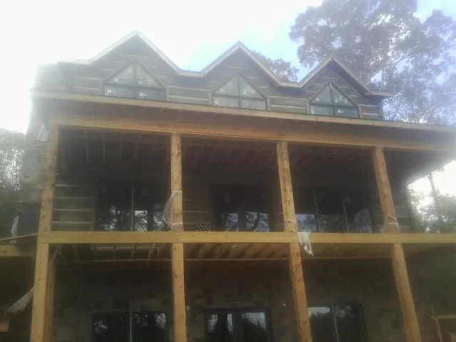 Dormers and porch framing on a large log home under construction — Roof Coating work by our crew in Campus