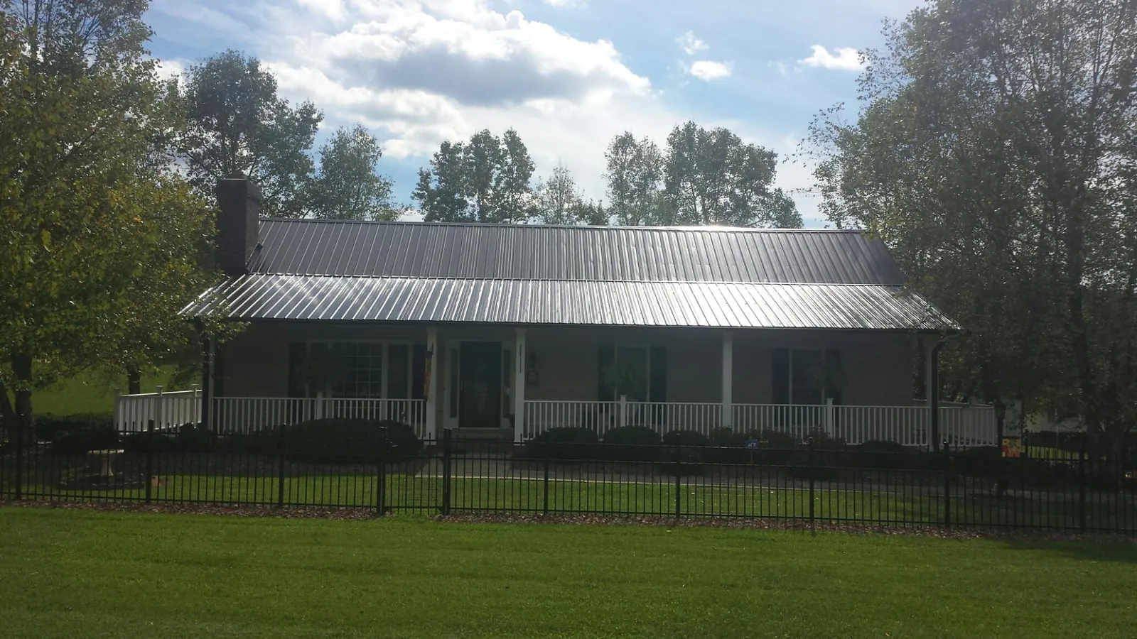 Gray metal roof on a brick ranch with a full width front porch — Gutter Guard Installation work by our crew in Campus