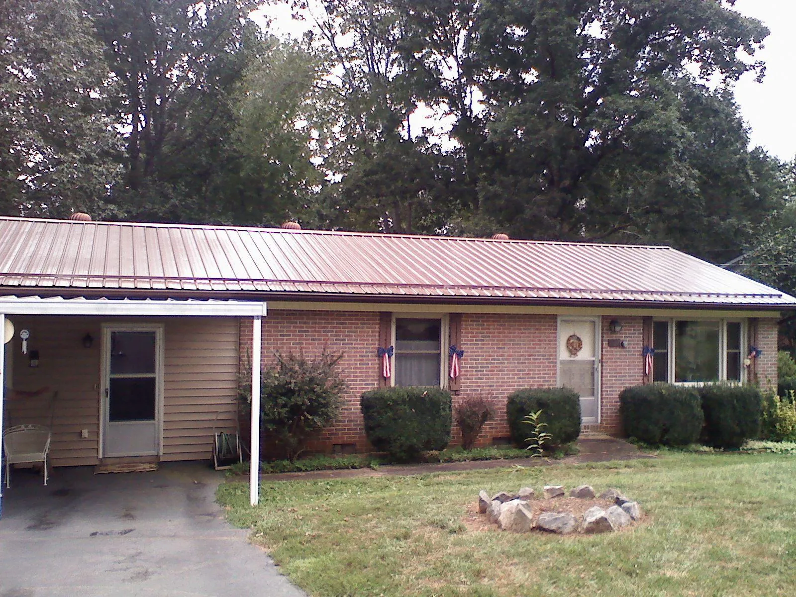 Bronze metal roof and carport on a brick ranch home — Roof Repair work by our crew in Campus